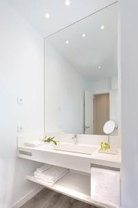 Un baño blanco con lavabo y espejo. en Lauser City Suites, en Los Llanos de Aridane