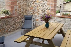 una mesa de picnic de madera con un jarrón de flores. en Gîte de charme du Domaine Pagnon Frigoulette, en Torreilles