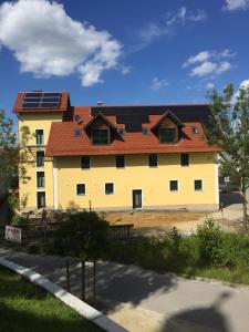 un gran edificio amarillo con paneles solares en el techo en Appartments Siegenburg, en Siegenburg