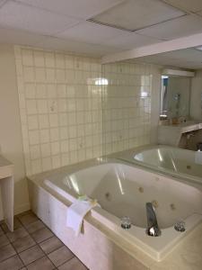 a bath tub in a bathroom with a mirror at Riverside Motor Lodge - Pigeon Forge in Pigeon Forge