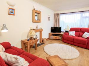 a living room with two red couches and a tv at 49 Cumber Close in Malborough