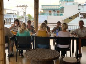 un grupo de personas sentadas en una mesa en un restaurante en Hostal Costa del Pacifico en Puerto Ayora