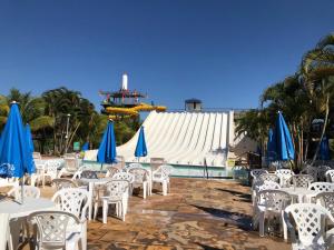 a group of tables and chairs with blue and white umbrellas at Piazza diRoma - Apartamentos JN in Caldas Novas