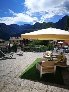 een patio met stoelen en een grote parasol bij Casa Luca e Cristina in Mezzolago