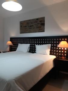 een slaapkamer met een groot wit bed met 2 lampen bij Largo da Fonte in Sertã