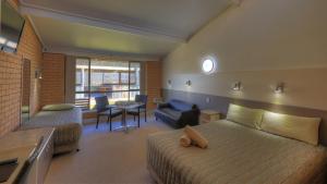 a bedroom with a bed and a couch and a chair at Tenterfield Motor Inn in Tenterfield