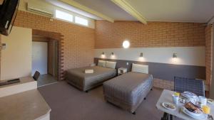 Zimmer mit 2 Betten und einem Tisch in der Unterkunft Tenterfield Motor Inn in Tenterfield