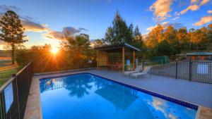 a swimming pool with a gazebo and the sunset at Boonah Motel in Boonah