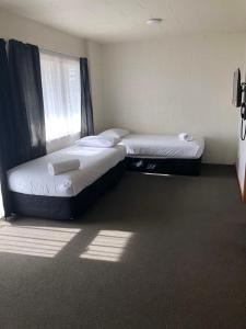 two twin beds in a room with a window at Victoria Apartments in Hamilton