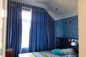 a bedroom with blue curtains and a bed with a window at Villa Nils in Cianjur