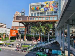 een drukke stadsstraat met een gebouw met een bord bij Interchange Tower Serviced Apartment - SHA Extra Plus in Bangkok