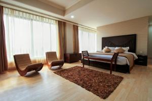 a bedroom with a bed and two chairs and a rug at The Piccadily in Lucknow