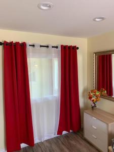 Habitación con cortinas rojas y espejo. en LAX guest house en Inglewood