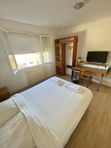 Schlafzimmer mit einem großen weißen Bett und einem Schreibtisch in der Unterkunft Hotel du Centre Lucé Chartres in Lucé