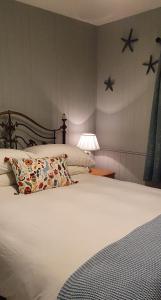 een slaapkamer met een wit bed met een kussen en een lamp bij Bay View House in Liscannor