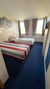Habitación de hotel con 2 camas y alfombra azul en Motel 44 en Geseke