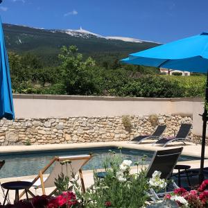 a swimming pool with chairs and an umbrella at La Garance in Bédoin