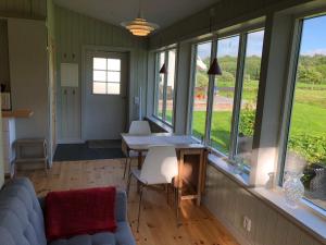 a living room with a couch and a table and windows at Mysig nybyggd stuga nära hav och natur in Klövedal