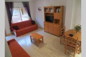 een woonkamer met een rode bank en een tafel bij 3 Bed Townhouse, Cabo Roig, Costa Blanca in Cabo Roig