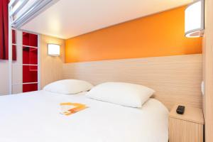 a bedroom with a white bed and an orange wall at Première Classe Epernay in Épernay +22 photos
