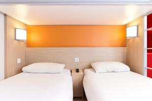 two beds in a room with orange walls at Première Classe Epernay in Épernay