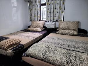 twee bedden in een kamer met gordijnen en kussens bij New Day Night Hostel in Hong Kong