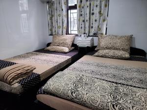 香港にあるNew Day Night Hostel RECEPTION 24 HOUR BLOCK D CHUNGKING MANSION TSIM SHA TSUI KOWLOONNのカーテンと枕付きの客室内のベッド2台