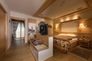 a bedroom with a bed and a television in it at Hotel Patrizia Dolomites Glamour in Moena
