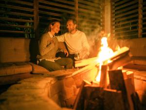 Ein Mann und eine Frau sitzen neben einem Feuer in der Unterkunft Garden Village Bled in Bled