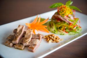 un piatto di cibo con carne e insalata su un tavolo di Jing Shang Hotel a Sihanoukville
