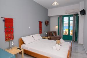 een slaapkamer met een bed, een stoel en een raam bij Porto Katapola Pension in Katápola