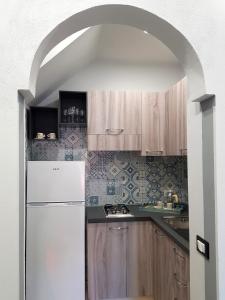 una cucina con armadi in legno e frigorifero bianco di Rigoletto a Campofelice di Roccella