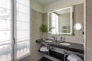 La salle de bains est pourvue de 2 lavabos et d'un grand miroir. dans l'établissement Chalgrin Boutique Hotel, à Paris