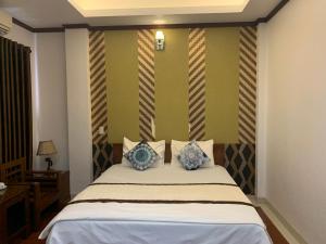 a bedroom with a bed with blue and white pillows at Hưng Thành Riverside Hotel in Thái Bình