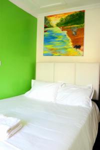 una camera da letto con un letto bianco e un dipinto sul muro di Little Green Room Homestay near JKIA Airport & SGR Railway Station a Nairobi