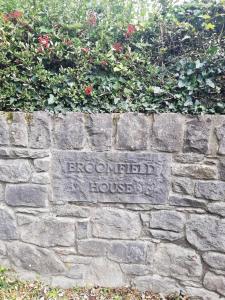 a sign on a brick wall with flowers at Next door at Broomfield House in Midleton