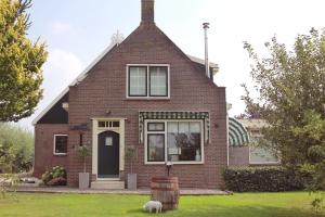 a red brick house with a dog in the yard at Bed en Breakfast Het Friesche Paard in Purmer