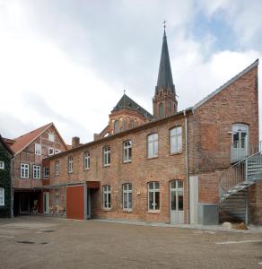 ein altes Backsteingebäude mit Kirchturm in der Unterkunft Hotel Bremer Hof in Lüneburg