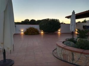 un patio con sombrillas, arbustos y luces en Villa gio puglia salento esclusiva villa privata con 6 camere doppie 3 bagni posti auto terrazza giardino 5 minuti dal mare en San Pietro in Bevagna