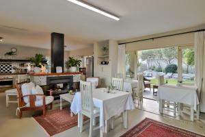 a dining room with white tables and chairs and a fireplace at Hermanus Lodge on the Green - Solar Power in Hermanus