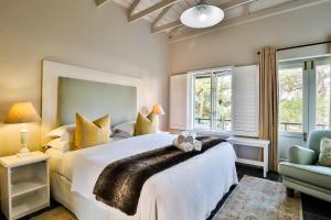 a bedroom with a bed with a teddy bear on it at Hermanus Lodge on the Green - Solar Power in Hermanus