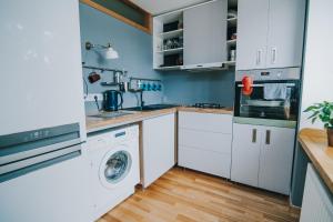 cocina con armarios blancos, lavadora y secadora en City center Appartment, en Valmiera