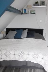a bedroom with a white bed with blue pillows at Bed en Breakfast Het Friesche Paard in Purmer