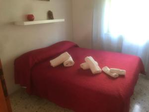 Un dormitorio con una cama roja con tres toallas. en due passi dal mare, en San Vito lo Capo