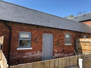a brick house with a gray door and a fence at The Cow 'ouse, Wolds Way Holiday Cottages, 1 bed cottage in Little Weighton