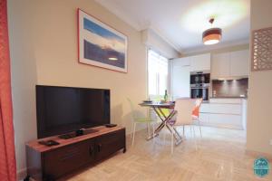 a living room with a television and a table with chairs at Annecy Lake - Le Saint Bernard - 2 min walk from the lake in Annecy