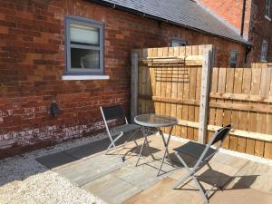 a patio with two chairs and a table and a fence at The Cow 'ouse, Wolds Way Holiday Cottages, 1 bed cottage in Little Weighton