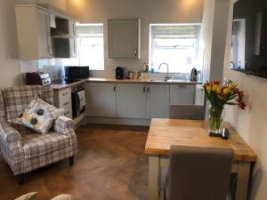 una cucina con tavolo, sedie e vaso di fiori di The Cow 'ouse, Wolds Way Holiday Cottages, 1 bed cottage a Little Weighton