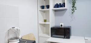 a kitchen with a black microwave on a white counter at Trzypokojowy apartament KATOWICE Damrota 4 in Katowice