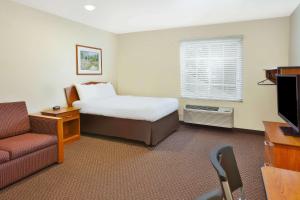 um quarto de hotel com uma cama, um sofá e uma televisão em WoodSpring Suites St Louis St Charles em St. Charles